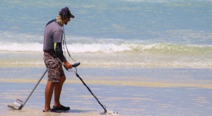 man using detector on beach 